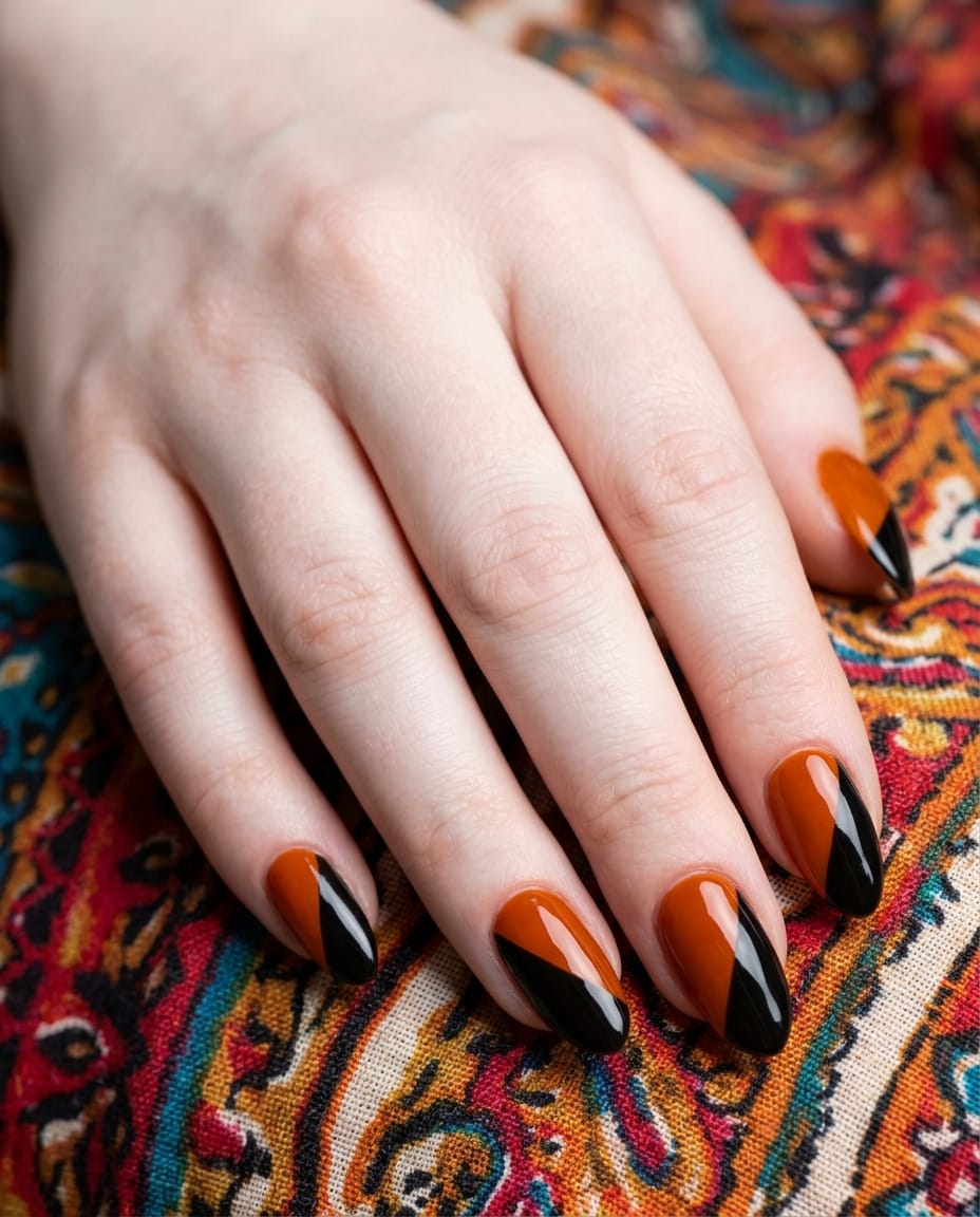 Hand with acrylic nails diagonally split between black and orange