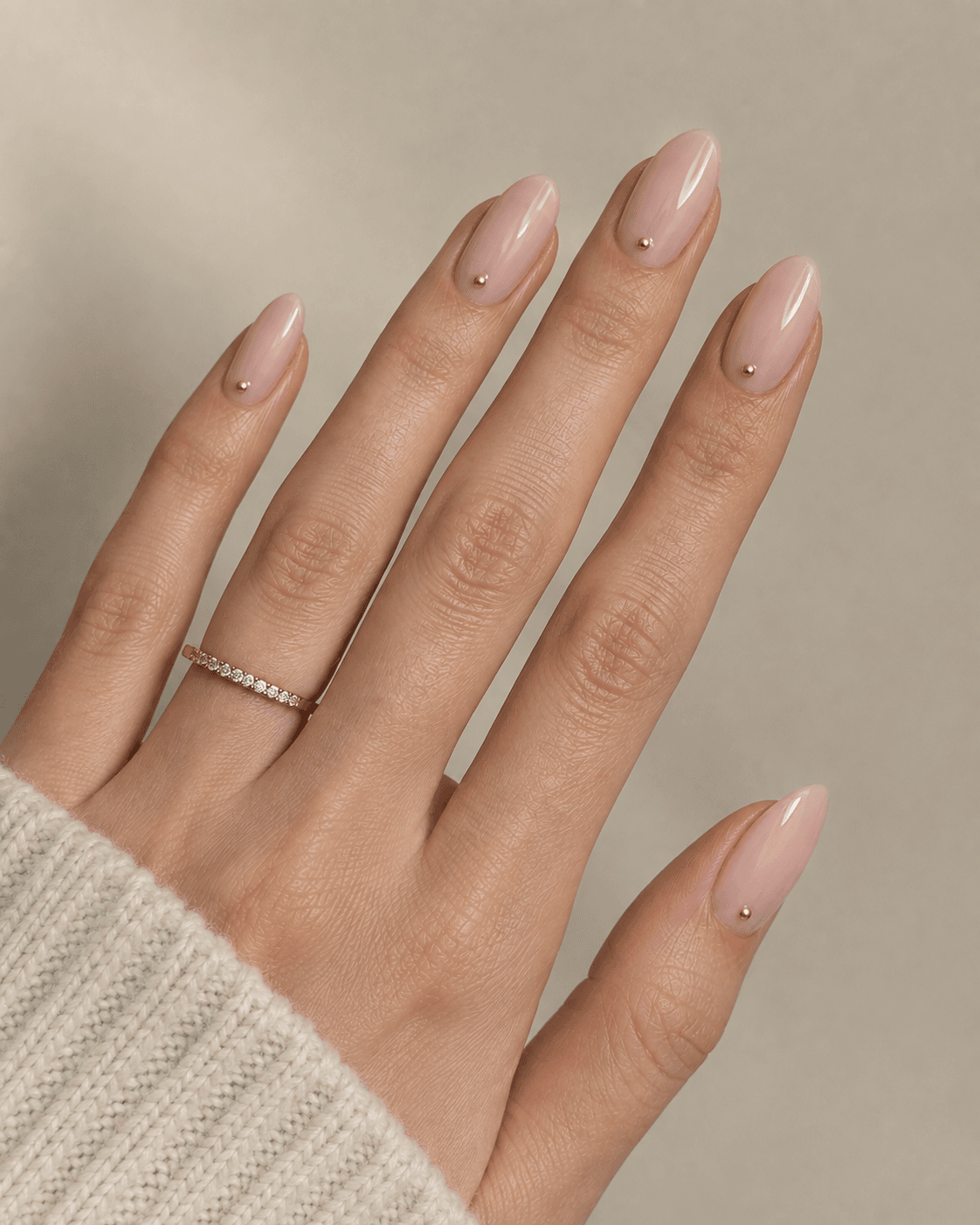 Hand with blush acrylic nails featuring a single gold dot accent near the cuticle.