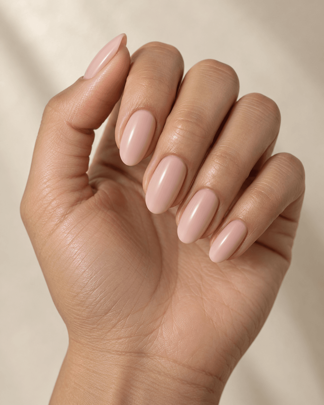 Hand with blush beige-pink oval acrylic nails.