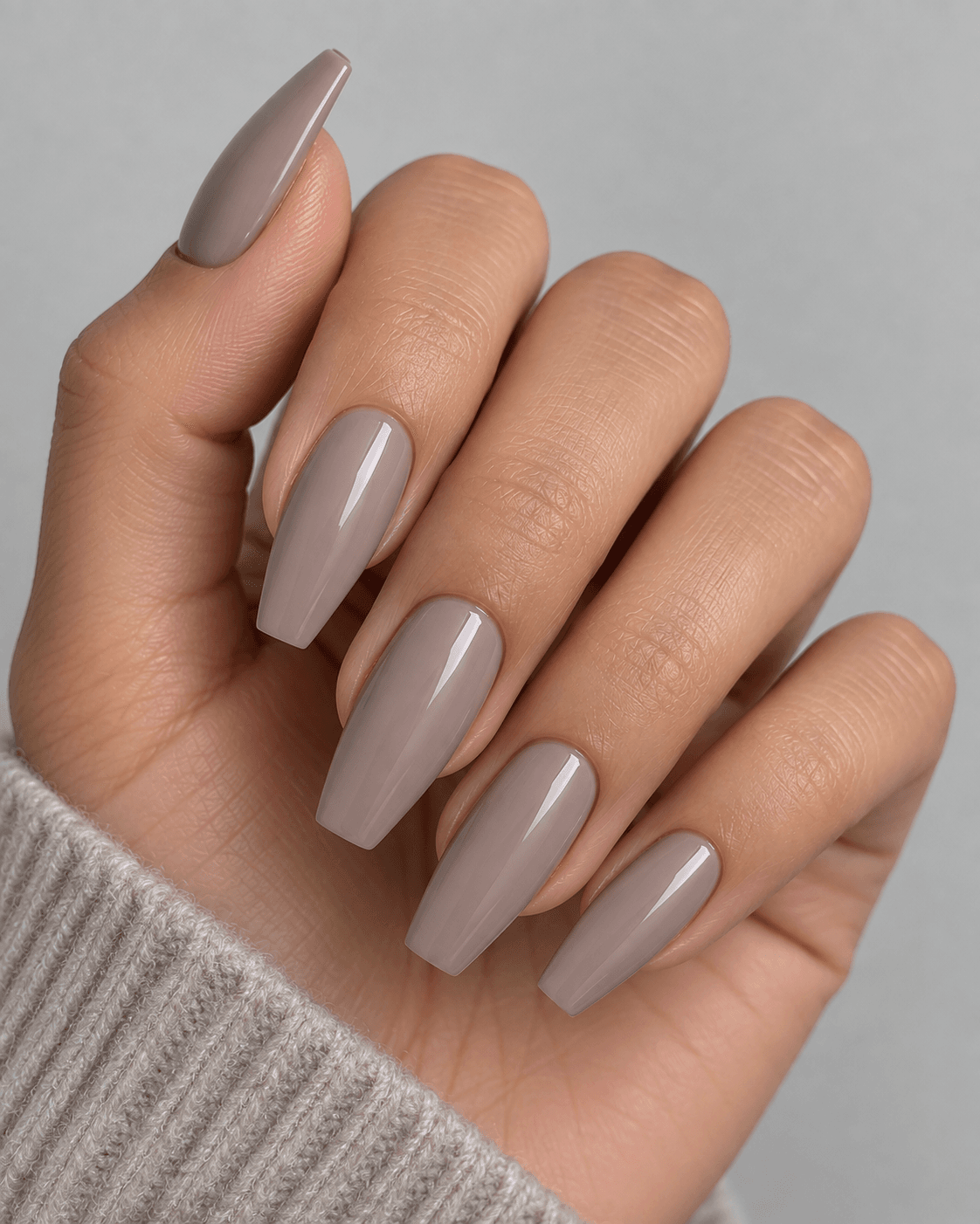 Hand with cool taupe-grey acrylic nails in a coffin shape.