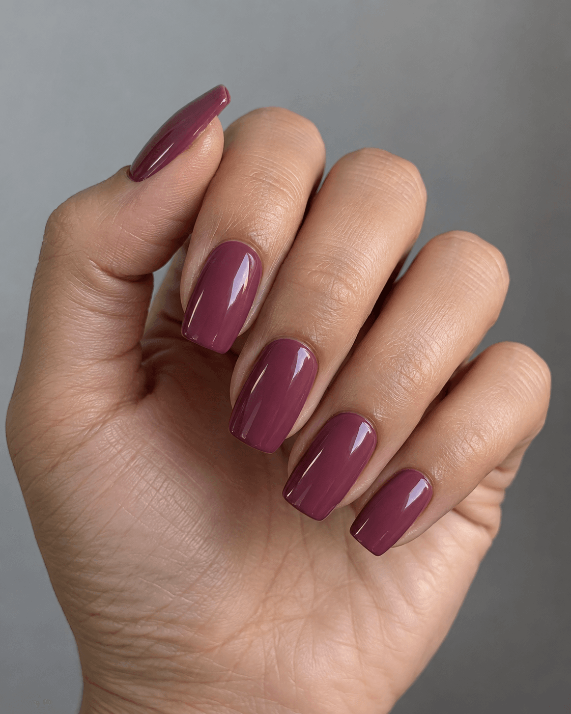 Hand with deep mauve glossy square acrylic nails.