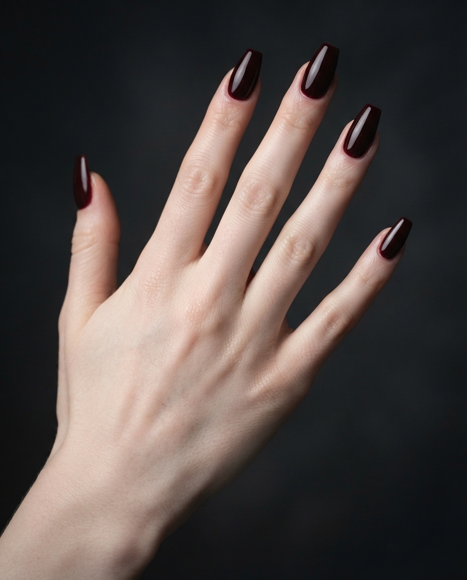 Hand with deep oxblood red coffin-shaped acrylic nails