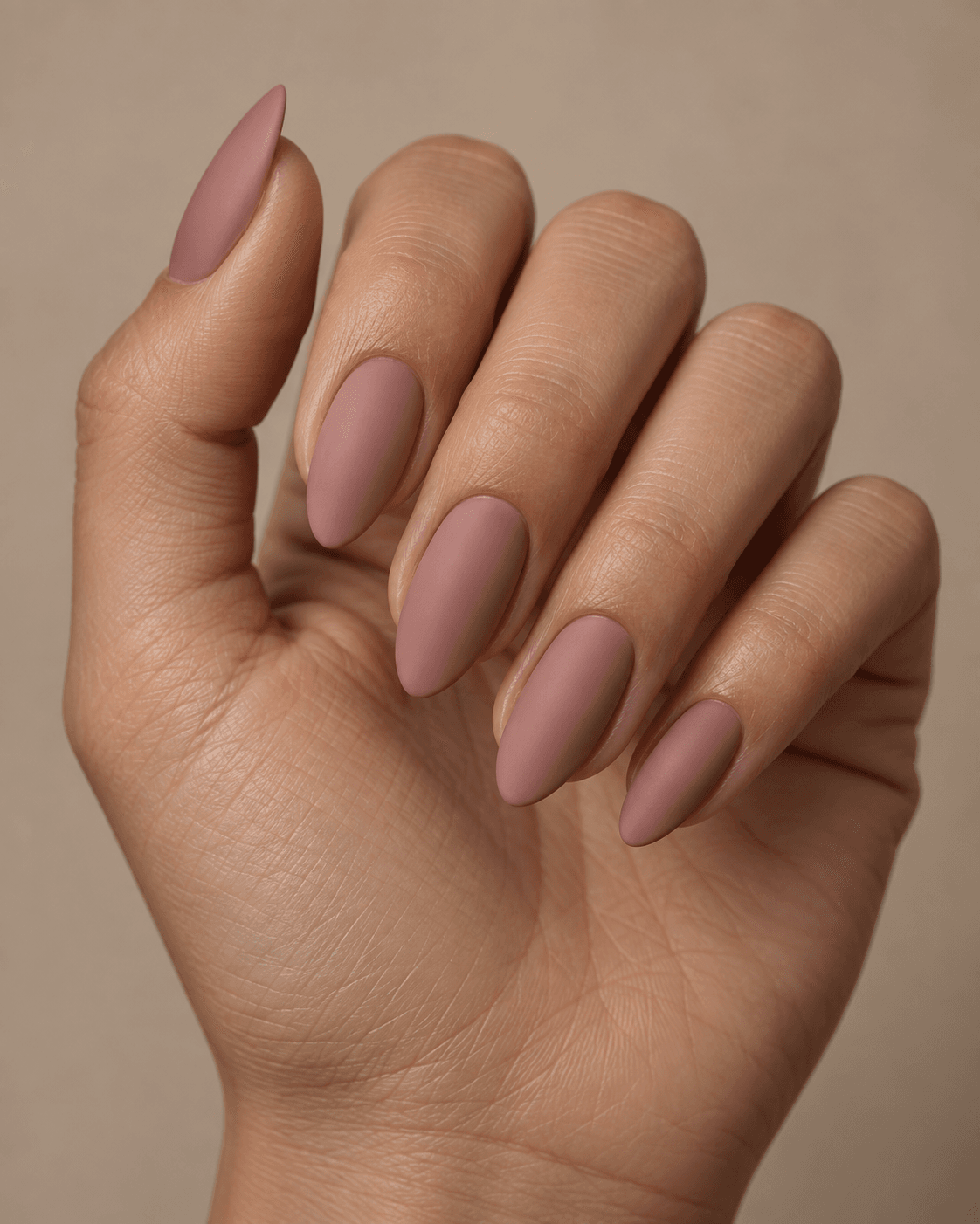 Hand with dusty rose matte almond acrylic nails.
