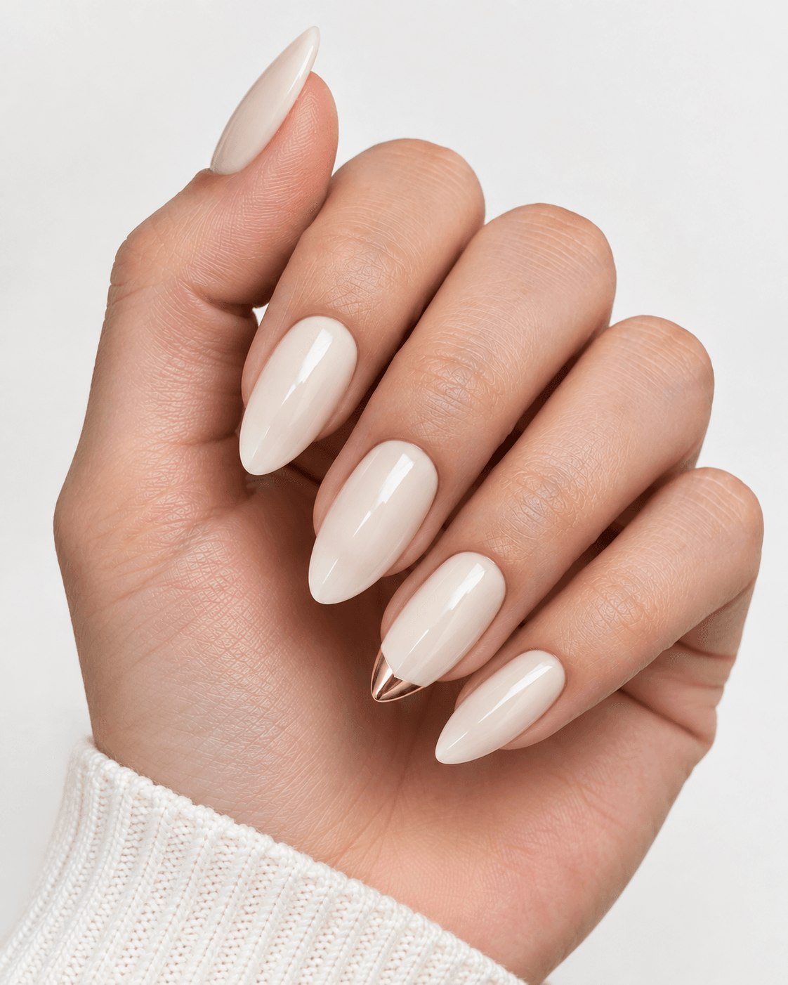 Hand with ivory acrylic nails and a small gold triangle tip accent.