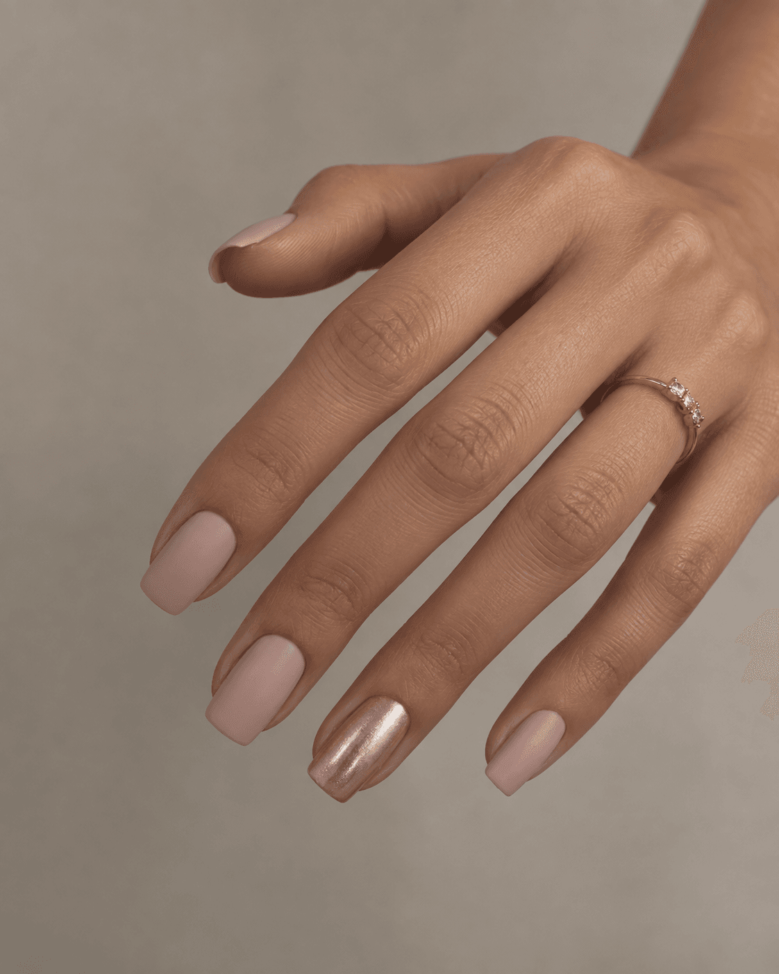 Hand with matte nude nails and one subtle chrome accent nail.