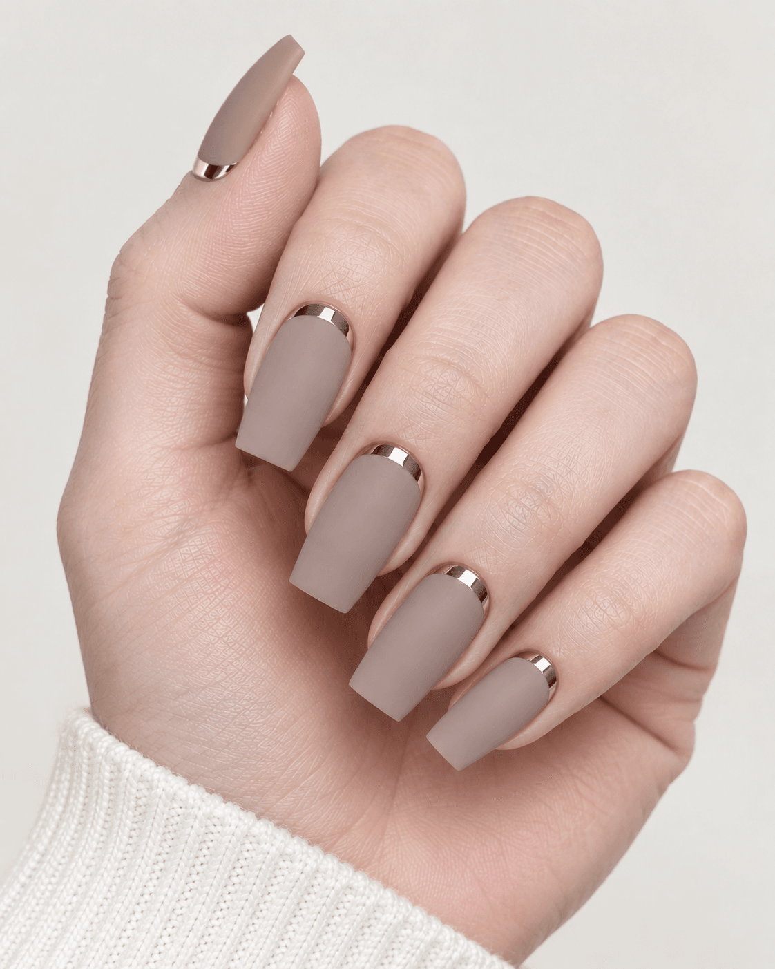 Hand with matte taupe acrylic nails featuring a chrome cuticle cap detail.