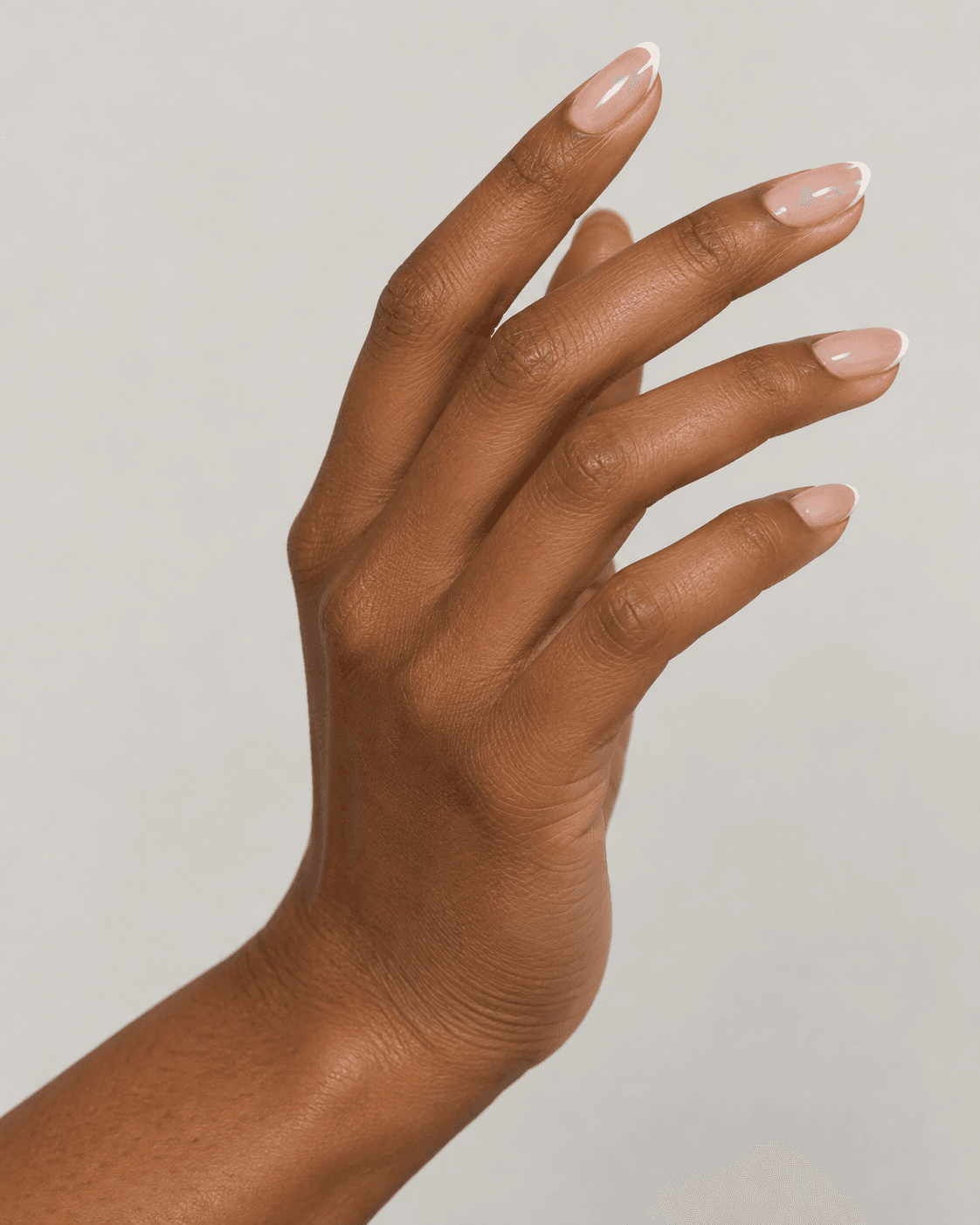 Hand with micro French tip almond acrylic nails over a sheer nude base.