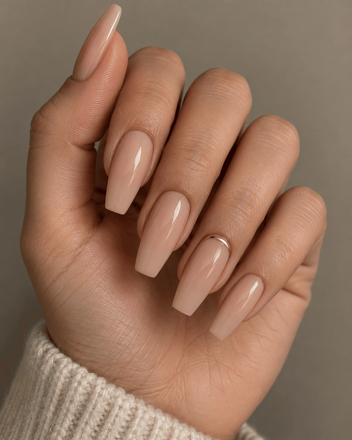Hand with nude acrylic nails and a single fine gold line accent.