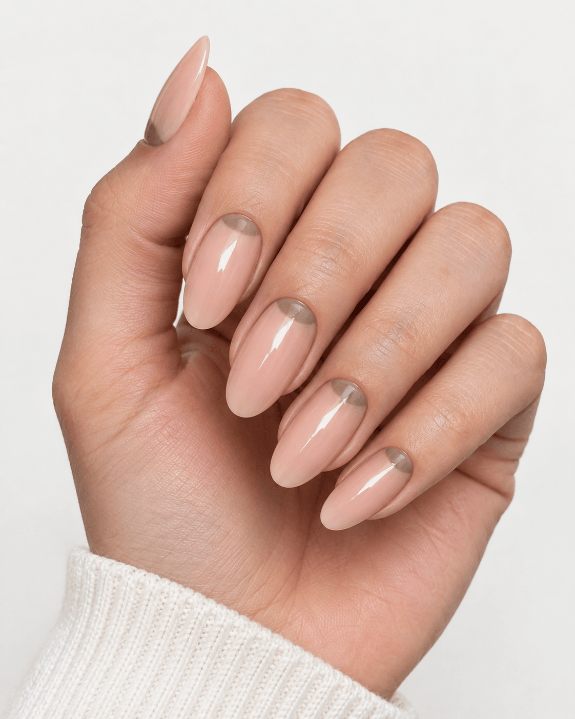 Hand with nude acrylic nails featuring a muted half-moon cuticle design.