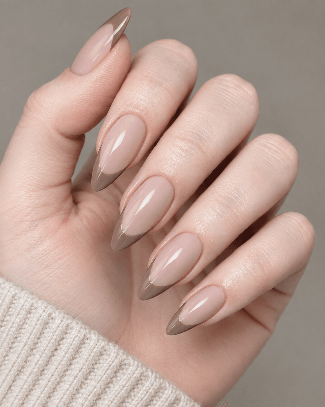 Hand with nude acrylic nails featuring soft color-blocked taupe tips.