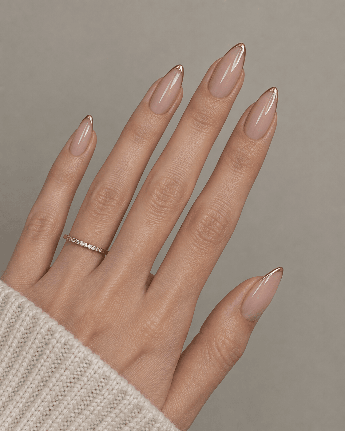 Hand with sheer nude acrylic nails featuring an outlined gold French tip.