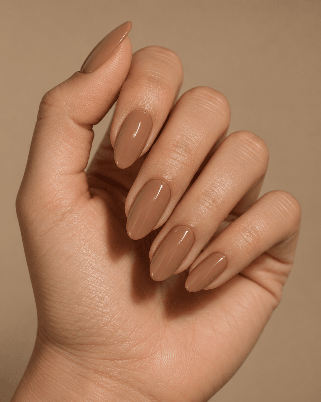 Hand with soft camel-nude acrylic nails.
