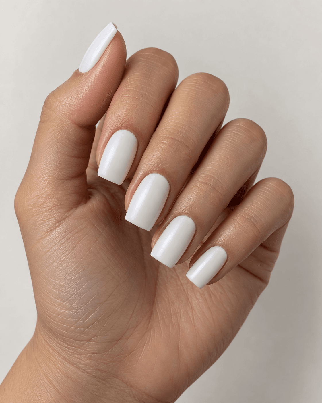 Hand with soft white satin-finish square acrylic nails.