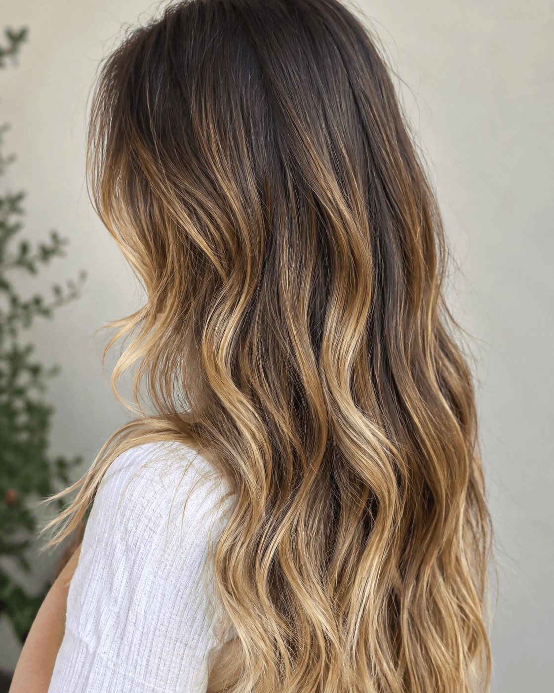 Woman with natural brown hair featuring golden balayage highlights